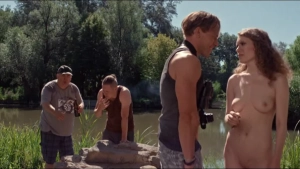 Curly-haired actress (Hermányi Mariann) standing fully naked by the river with men in Empire Birodalom 2026, outdoor daylight, natural full frontal nudity scene.
