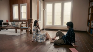 Yuki Mamiya in dialogue scene from Naomi Reversed (2024), two characters sitting on wooden floor facing each other in bright living room. - img #1