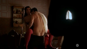 Partial nudity scene from Borgia S03 featuring a shirtless man embracing a woman in black lingerie and red stockings in a dimly lit room.