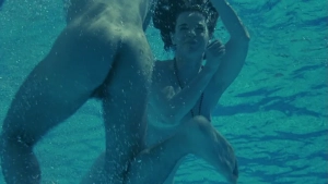 Anna Galiena nude underwater sex scene, intimate embrace visible as couple swims together in blue pool water from Black Angel film.