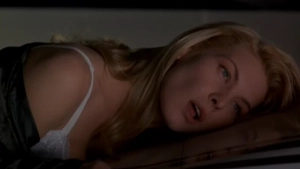 : Deborah Kara Unger close-up lying on surface wearing white lingerie strap visible, blonde hair in dimly lit room from Crash (1996) - img #1