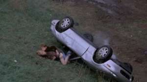 Deborah Kara Unger in outdoor sexual encounter scene from Crash (1996), overturned car dramatic moment with partial nudity.