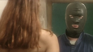Over-the-shoulder close-up from an intimate indoor scene capturing a masked figure in a black ski mask and blue suit facing a woman with long red hair, likely a nude or semi-nude character based on visible shoulder lines.