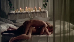 Alt-Text (SEO): Intimate bedroom scene from Private Vices Public Pleasures (1976) - Full nude individuals engaged in explicit sexual activity on a bed with lit candles creating dramatic atmospheric lighting.