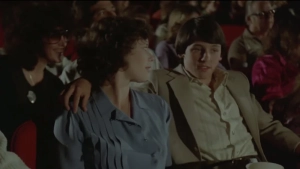 Close-up of actress Sylvia Kristel in an intimate conversation scene from *Private Lessons* (1981), wearing her signature short, curly hairstyle. She is seated outdoors at a glass patio table, engaged in a focused discussion with the young man across from her. - img #14
