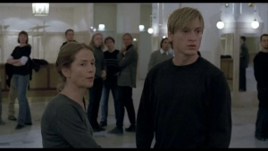Isabelle Huppert and Benno Fürmann stand in a bright dance studio lobby during rehearsal scene from The Piano Teacher.