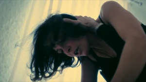 Trinca woman on top of man sex scene in Gli occhi degli altri 2025 - actress wearing black dress leaning over man with intense expression under warm yellow lighting
