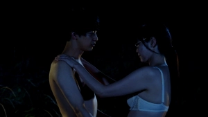 Yuka Kouri in white lingerie faces a shirtless man in a dark, intimate scene from Young and Fine (2025).